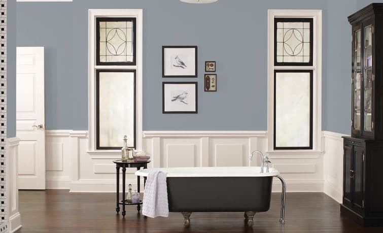 Painter cutting a clean line where a sage-gray wall meets a white ceiling