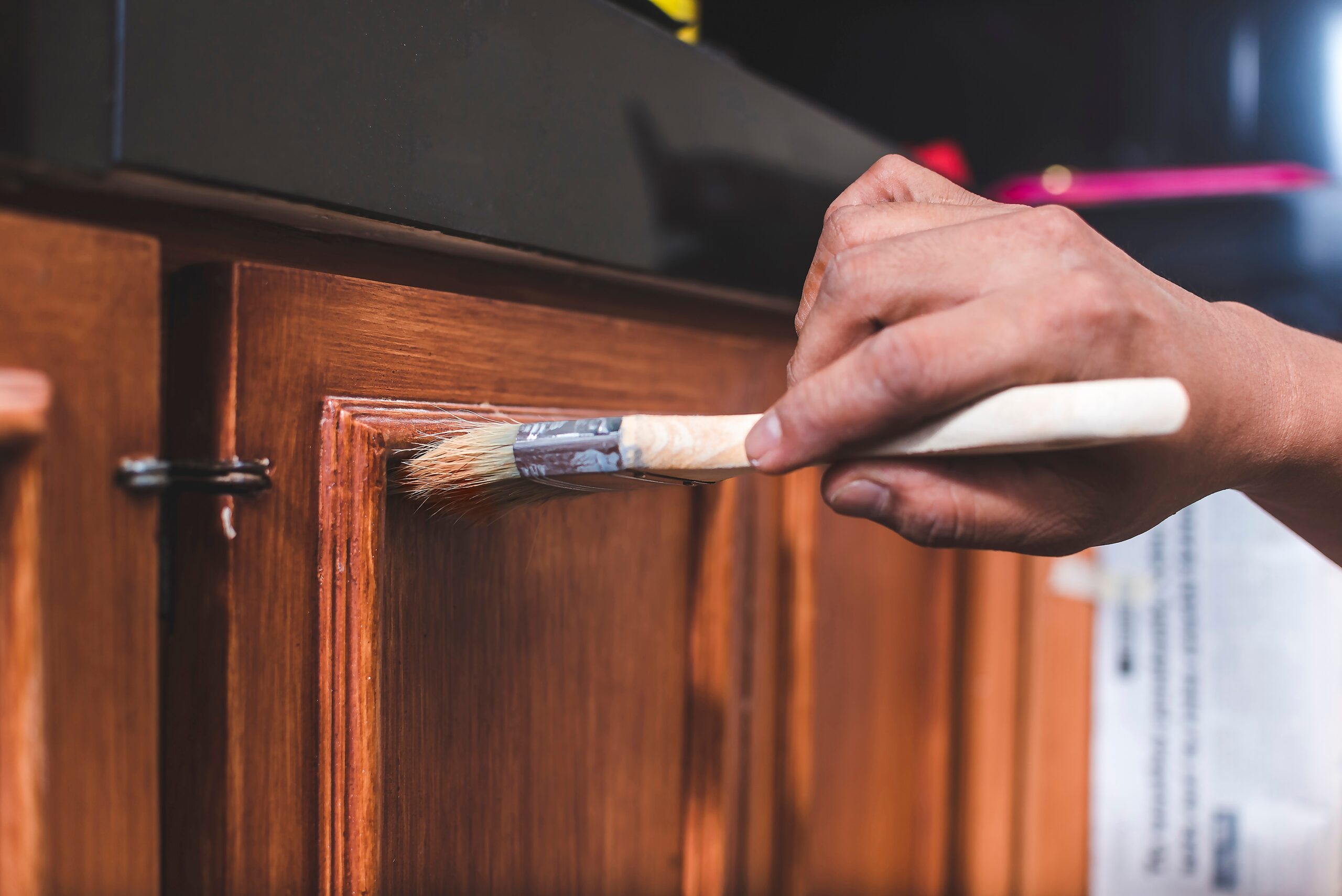 Painter brushing a fresh coat onto a wood cabinet door