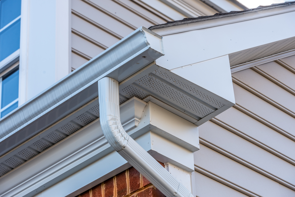 Freshly painted white fascia and gutters at a roofline corner