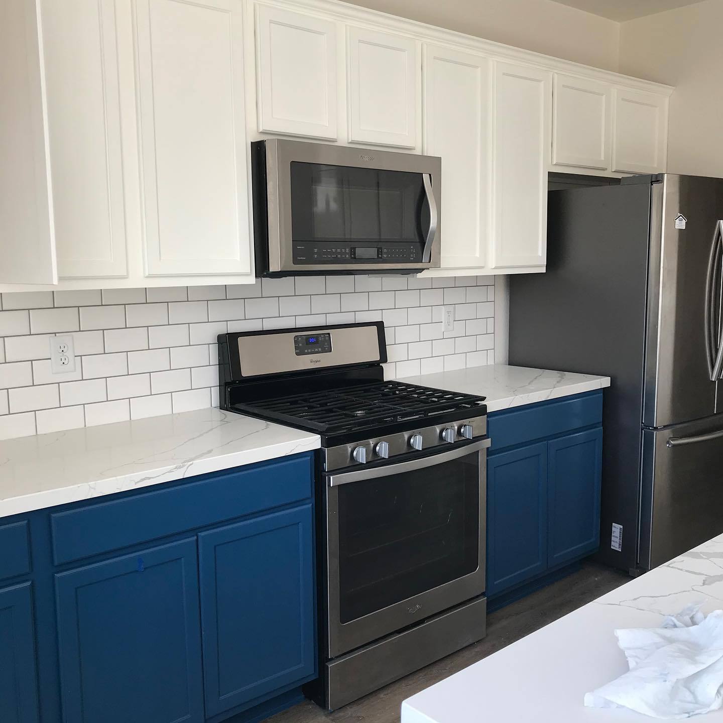 Kitchen with navy lower cabinets and white uppers after refinishing