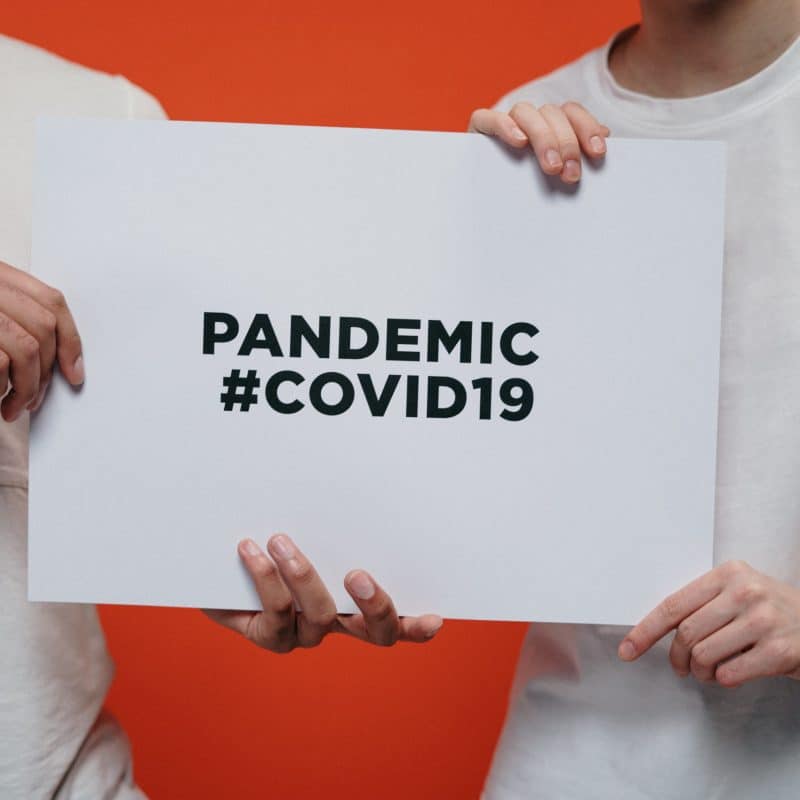 People-Holding-White-Paper-With-Pandemic-Covid19-Text-scaled-1